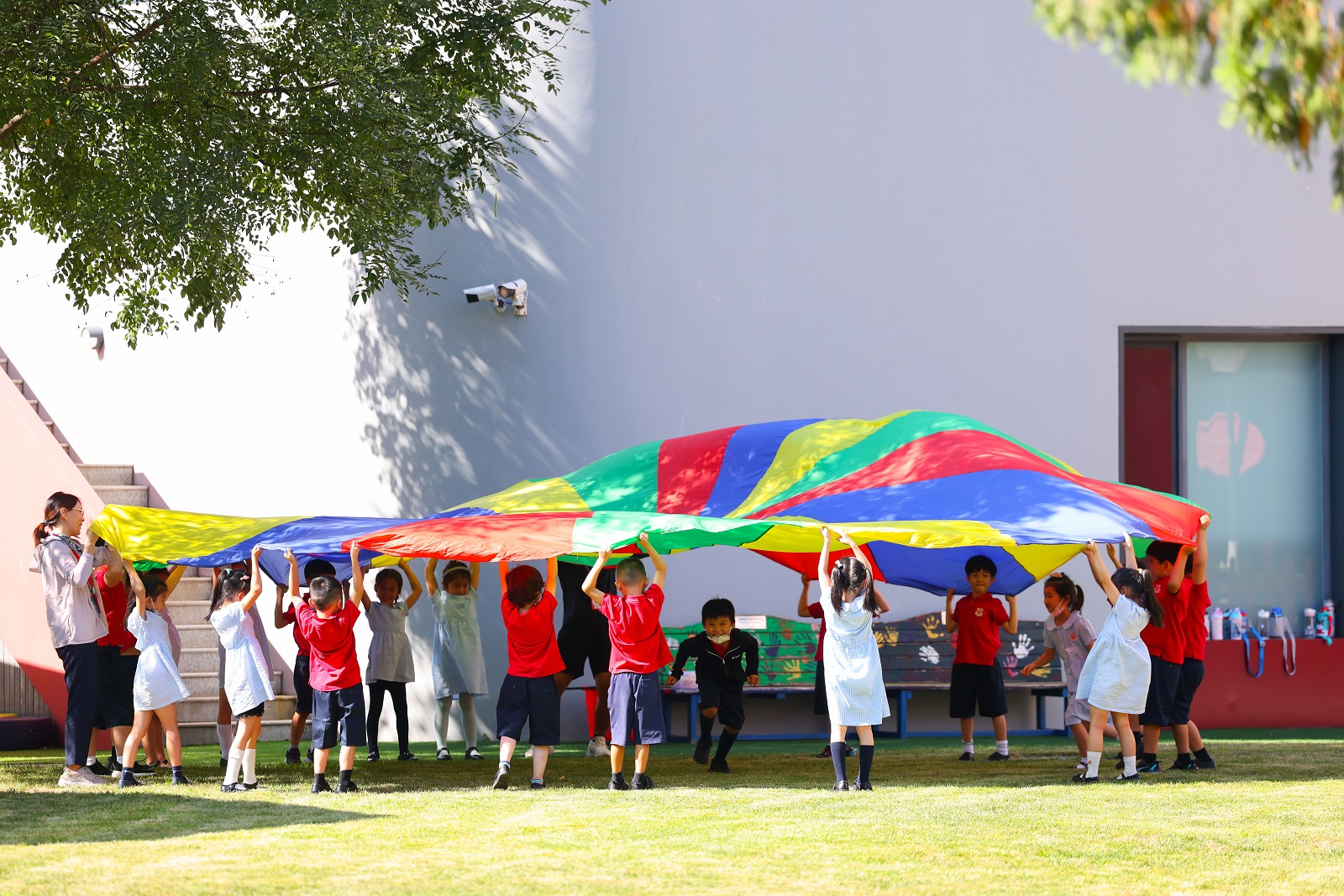 幼儿园学生在校园里玩降落伞
