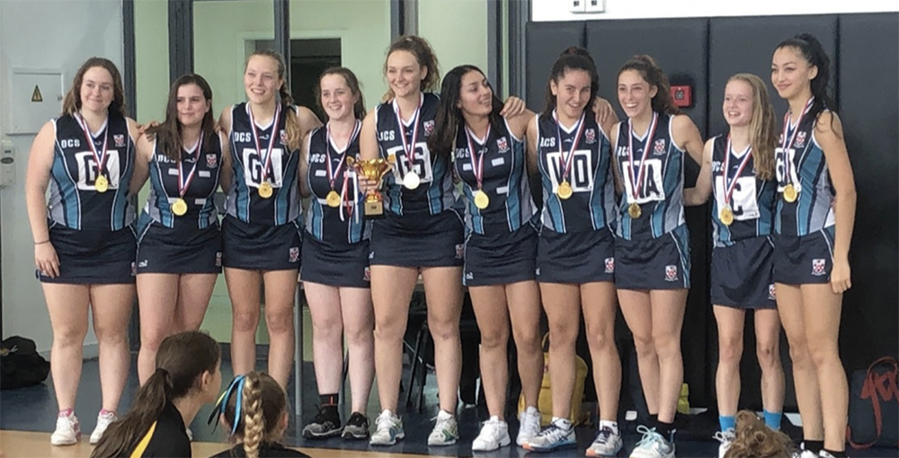 Natasha holds the trophy in a Netball competition (fifth from left)